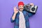 Middle age man wearing cap listening vintage boombox over isolated purple background doing ok sign with fingers, smiling friendly