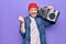 Middle age man wearing cap listening vintage boombox over isolated purple background screaming proud, celebrating victory and