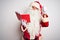 Middle age man wearing Santa Claus costume reading book over isolated white background angry and mad raising fist frustrated and