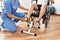 Middle age man and woman having rehab session pedaling sitting on wheelchair at physiotherapy clinic