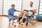 Middle age man and woman having rehab session pedaling sitting on wheelchair at physiotherapy clinic