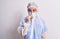 Middle age nurse woman wearing protection coronavirus equipment over white background looking stressed and nervous with hands on