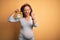 Middle age pregnant woman expecting baby at aged pregnancy holding alarm clock annoyed and frustrated shouting with anger, crazy