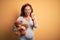 Middle age pregnant woman expecting baby holding teddy bear stuffed animal annoyed and frustrated shouting with anger, crazy and