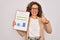 Middle age senior business woman holding monthly goal graphic on clipboard happy with big smile doing ok sign, thumb up with