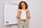 Middle age senior business woman standing on seminar presentation by magnectic blackboard doing money gesture with hands, asking