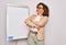 Middle age senior business woman standing on seminar presentation by magnectic blackboard looking to the side with arms crossed