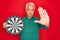 Middle age senior grey-haired man holding competition dartboard target over red background with open hand doing stop sign with
