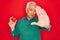 Middle age senior grey-haired man holding romantic red heart object over isolated red background with open hand doing stop sign