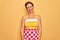 Middle age senior pin up housewife woman wearing 50s style retro dress and apron with a happy and cool smile on face