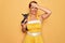 Middle age senior pin up woman wearing 50s style retro dress holding chihuahua dog stressed with hand on head, shocked with shame