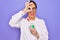 Middle age senior scientist woman wearing laboratory coat holding research test tube with happy face smiling doing ok sign with