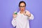 Middle age senior scientist woman wearing laboratory coat holding research test tube pointing with finger to the camera and to