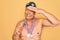 Middle age senior swimmer man wearing swimsuit, cap and goggles holding winner medals stressed with hand on head, shocked with