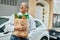 Middle age southeast asian man smiling holding a bag of fresh groceries at the city