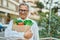 Middle age southeast asian man smiling holding a bag of fresh groceries at the city