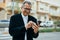 Middle age southeast asian man smiling using smartphone at the city