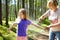 Middle age woman applying insect repellent to her granddaughter before forest hike beautiful summer day. Protecting children from