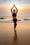 Middle age woman in black doing yoga on sand beach