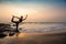 Middle age woman in black doing yoga on sand beach in India Natarajasana pose