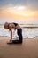 Middle age woman in black doing yoga on sand beach in India at sunset