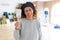 Middle age woman with curly hair smiling cheerful painting new house using paint brush, renovating and decorating the wall