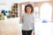 Middle age woman with curly hair smiling cheerful painting new house using paint brush, renovating and decorating the wall