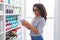 Middle age woman customer holding lotion bottle at pharmacy