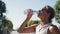 Middle age woman drinking water from plastic bottle after gym, outdoor workout, city sport, brunette caucasian girl