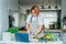 Middle age woman following a cooking tutorial video course on laptop while preparing meal in a kitchen. Woman cooking