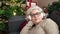 Middle age woman with grey hair sleeping on sofa by christmas tree at home