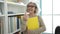 Middle age woman with grey hair teacher holding book doing come gesture at university classroom