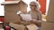 Middle age woman with grey hair unpacking cardboard box reading document at new home
