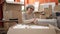 Middle age woman with grey hair using smartphone unpacking cardboard box at new home