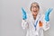 Middle age woman with grey hair wearing scientist robe celebrating mad and crazy for success with arms raised and closed eyes