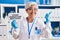 Middle age woman with grey hair working at scientist laboratory holding your donation matters banner smiling happy pointing with