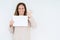 Middle age woman holding blank paper sheet over isolated background doing ok sign with fingers, excellent symbol