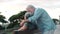 Middle age woman sitting on bench of park with old man hugging her from the back. Couple of retired people relaxing and enjoying