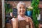 Middle age woman with tattoos working at florist shop holding dataphone smiling happy pointing with hand and finger