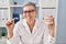 Middle age woman wearing dentist uniform holding brackets and aligner at clinic