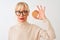 Middle age woman wearing glasses holding cookie standing over isolated white background with a confident expression on smart face