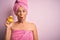 Middle age woman wearing pink bath towel from beauty body care holding rubber yellow duck scared in shock with a surprise face,