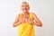 Middle age woman wearing yellow casual t-shirt standing over isolated white background smiling with hands on chest with closed