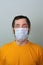 Middle-aged adult man in a yellow T-shirt on a gray background in a medical mask with bulging eyes. Coronavirus Disease Outbreak