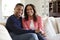 Middle aged African American  couple sitting on the sofa in their living room looking to camera, front view, close up