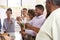 Middle aged African American  man opening champagne to celebrate with his three generation family, close up