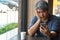 Middle-aged Asian men 40 years old, stressed and tired and using smartphone, are sitting in fast restaurant. On the table there