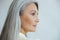 Middle aged Asian woman with beautiful straight hoary hair on light grey background