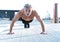 Middle-aged athletic man doing push ups outdoors. Fitness and exercising outdoors urban environment.