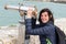 Middle aged beautiful woman looking in telescope binoculars seaside ocean beach during tourism vacation